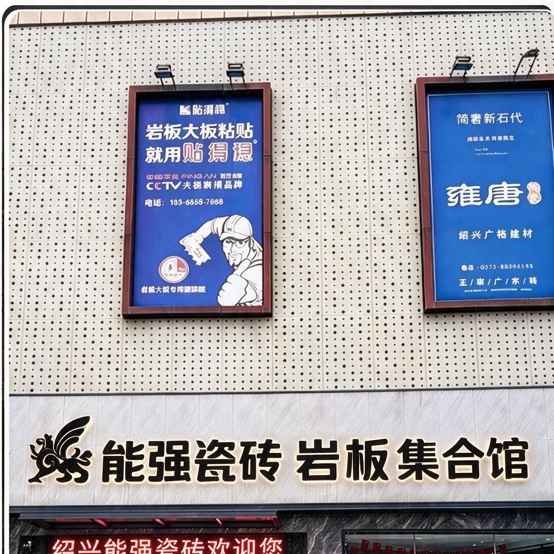 能强瓷砖岩板集合馆门头：黑色金属狮鹫logo与发光字招牌，LED屏显示绍兴能强瓷砖欢迎您